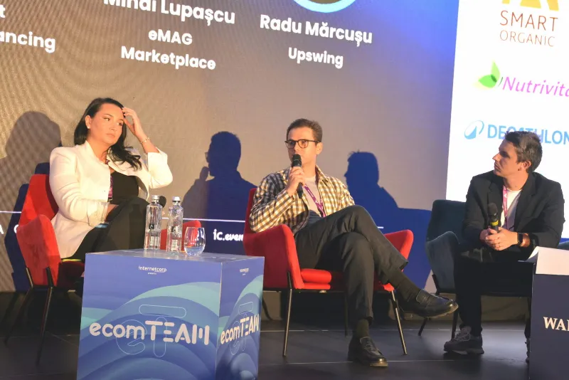 Trei participanți la panelul despre creșterea în e-commerce, în fotolii roșii pe scenă, în timpul discuției.